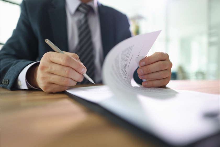 Profesional firmando documentos legales durante gestión de contratos empresariales